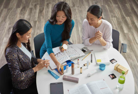 Independent business owners sit at a table together and review Amway products.